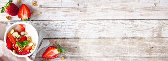 Healthy yogurt with fresh strawberries and granola. Banner with corner border against a rustic wood...