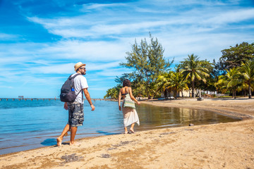 Two young people walking along the beach of Sandy Bay on Roatan Island. Honduras