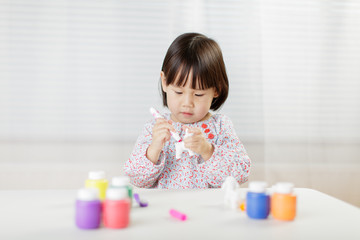 toddler girl watercolor painting on the animal toy at home against white background