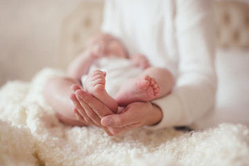 Small baby sleeping quiet on mother hands in bed closeup. Good morning. Focus on little tiny feet and toes.