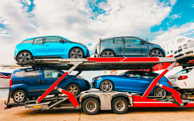 Car transporter on road at port of Cagliari in Sardinia Island, Italy summer. Truck trailer driving on motorway at highway. Mixed media.