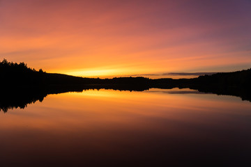 Peaceful orange, yellow and purple sunset over calm lake