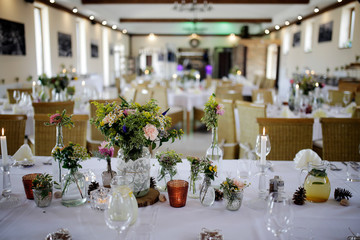 The festive table at the restaurant is decorated with candles and flowers. Wedding reception dinner. Wedding reception dinner. Tables served with candles and rose gold decor stands in restaurant. 