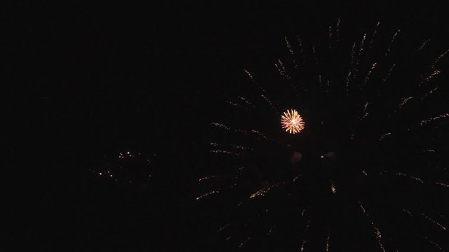 Bright colorful fireworks turn to multicolor bokeh lights at holiday dark summer night.