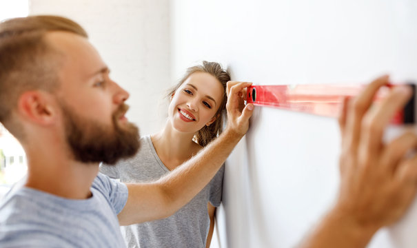 young happy couple is repairing and painting   wall at home