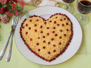 Festive salad in the shape of a heart, decorated with pomegranate seeds, the idea of decoration for Valentine's Day, Horizontal orientation, Top view