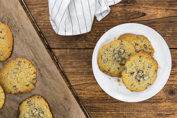 Old wooden table with fresh Chocolate Chip Cookies (close-up shot; selective focus)