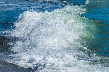 Blue sea wave with splashes and foam on the beach