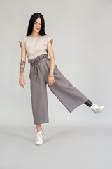Freestyle. Diverse girl with leg prosthesis standing on one leg isolated on grey full body shot...