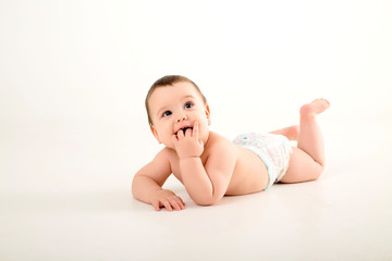 healthy baby brunette boy smiling and looking at the camera, baby in a diaper lying on a white...