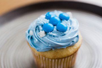 Vanilla cupcake with blue icing and decorative sprinkles
