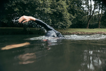 Male swimmer in the river with forest in background
