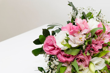 Ramalhete de flores com cores brancas, vermelhas e verdes e rosa sobre a mesa branca