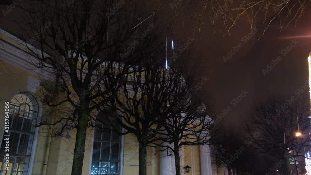 Poster view from the bottom on the trees with illuminated with shiny christmas lights in the dark against t