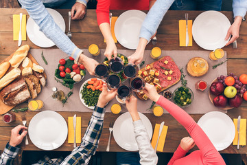 Family sitting behind table and clinking beverage glasses