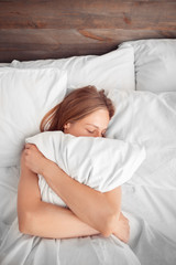 Morning at Home. Woman lying on bed hugging pillow sleeping top view