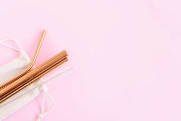 metal cocktail straws, a tube cleaning brush and an eco-friendly bag on a pink background, the concept of zero waste and an eco-friendly lifestyle