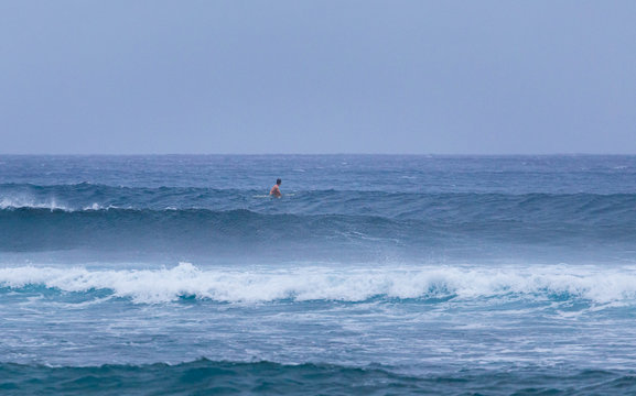 Lone Surfer Looking Out To Sea As He Waits For Waves In Rough Conditions