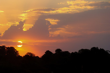 Por do sol com poeira e arvores e nuvens