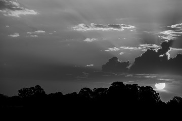 Foto em P&B paisagem com sol atras de nuvens