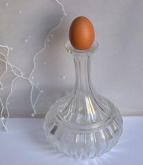 Egg in a transparent glass decanter on white textured background.