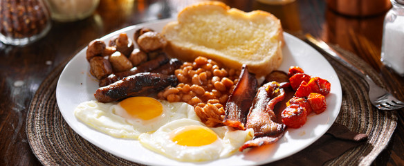english breakfast with eggs, tomatoes, mushrooms, bacon, beans, and sausage