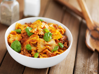 bowtie pasta in tomato sauce with basil on wooden table