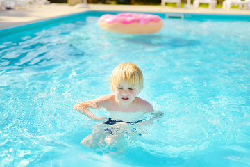 Fototapeta na wymiar Little boy swim in pool during holidays with family in Greece