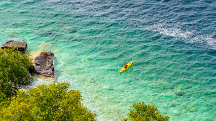 Unrecognizable woman silhouette kayaking in the ocean. Beautiful rocky beach with crystal clear...
