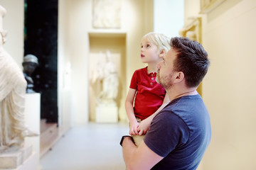 Little boy with his father looking at sculptures.