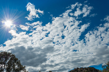 Blue sky landscape with white clouds and bright sun
