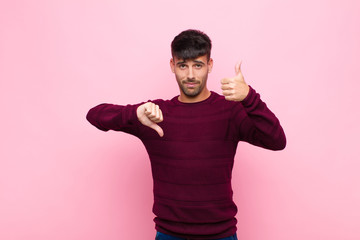 young handsome man feeling confused, clueless and unsure, weighting the good and bad in different...