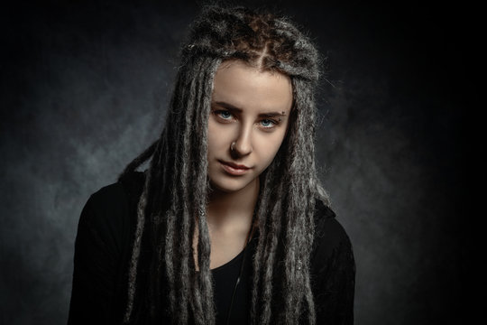 Portrait of a stylish young woman with dreadlocks against dark background
