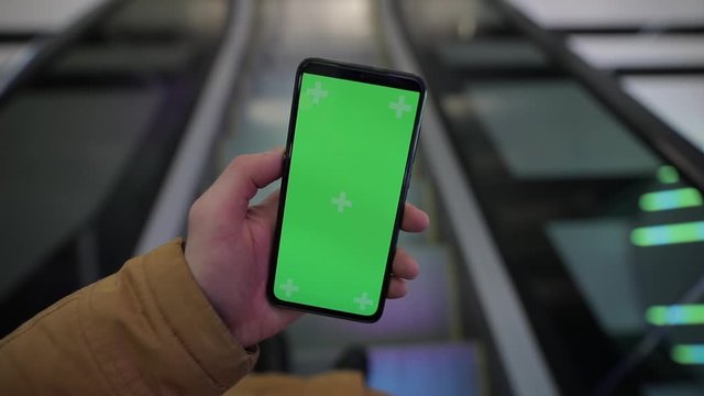 Using empty screen of smartphone in a mall on escalator, mockup
