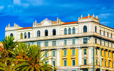 Obraz premium Cityscape of Old Sardenian city in Cagliari, South Sardinia Island in Italy in summer. View on town building architecture. And Green palm tree. Mixed media.