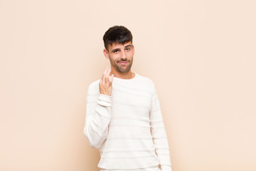 young handsome man looking arrogant, successful, positive and proud, pointing to self against warm...