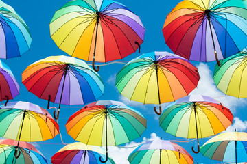 Um arco íris de guarda-chuvas enfeitando o céu azul.