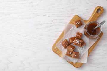 Delicious salted caramel on white wooden table, top view. Space for text