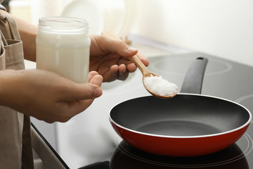 Woman cooking with coconut oil on induction stove, closeup