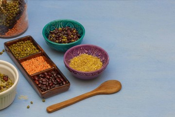 Red and green lentils and beans in a scrambler, bowls with bulgur and beans,close-up, blue background
