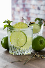 Close of view of a glass of sparkling water with lime and mint garnish.