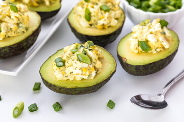 A top down view of egg salad in avocado boats ready for eating.