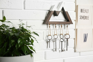 Wooden key holder on white brick wall indoors