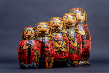 Traditional Russian matryoshka dolls lined up against gray background, doll within a doll, object within an object, metaphor for shell companies, Russian nesting doll 3