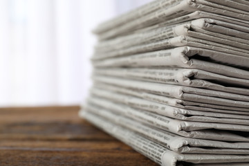 Stack of newspapers on wooden table, space for text. Journalist's work