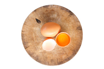 Brown eggs on a wooden chopping board There is a yolk in the egg shell. The brown egg has a drop of water because it is removing from the refrigerator.