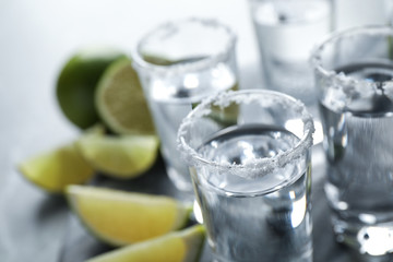 Mexican Tequila shots, lime slices and salt on grey table, closeup