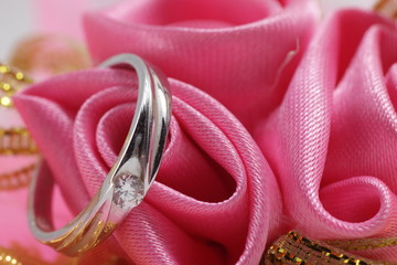White gold engagement ring with diamond on pink cloth as background