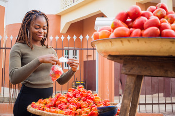 young pretty african trader feeling excited as she is packaging her tomatoes.