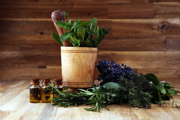 Fresh herbs from the garden and the different types of oils for massage and aromatherapy on table with lavender